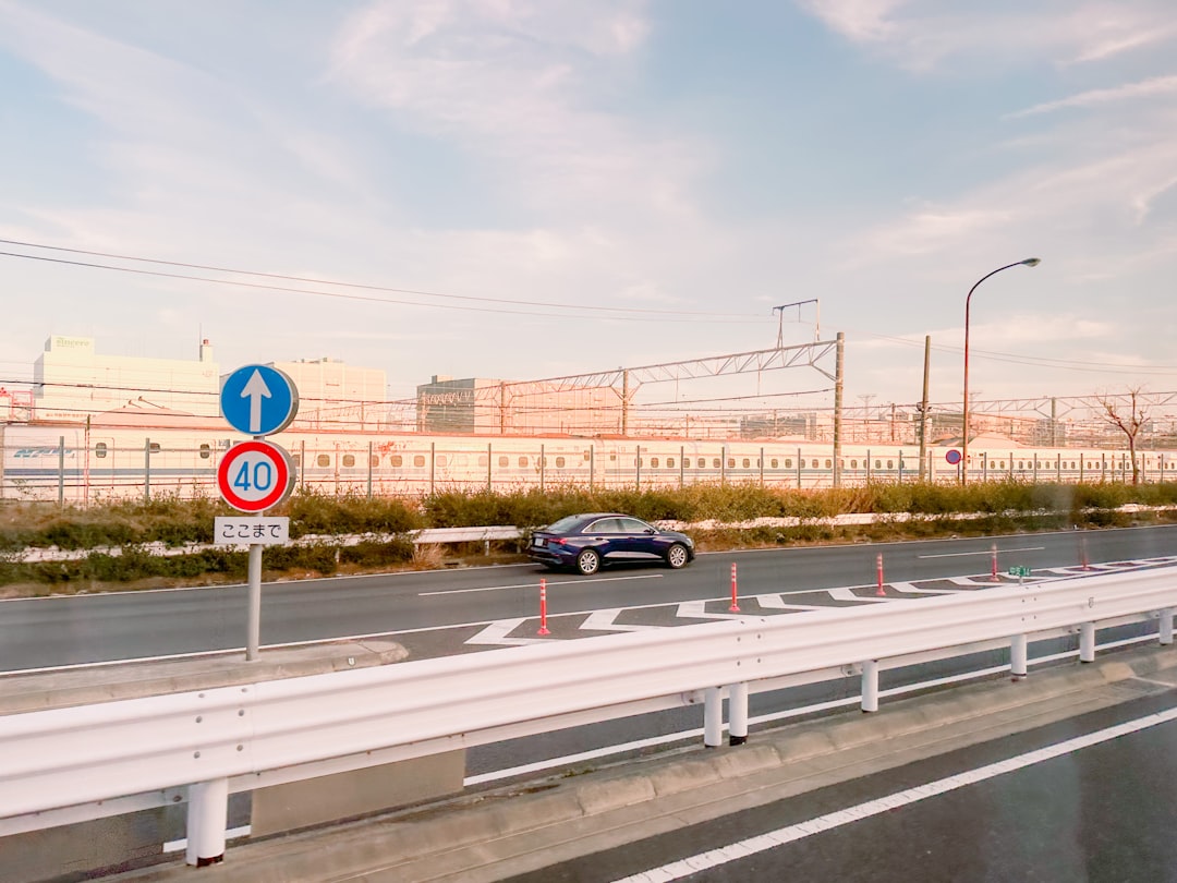An ETC toll booth lane on a Japanese expressway at dawn showing the green ETC sensor gantry and empty road ahead