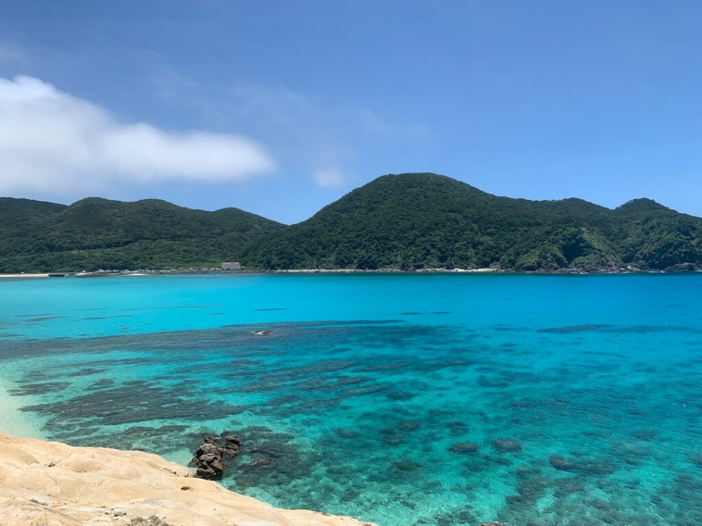 Turquoise water and white sand beach in the Kerama Islands with a tour boat anchored offshore