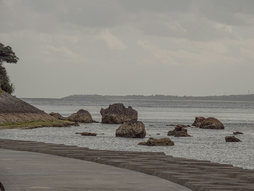 Rocky limestone coastline and open ocean near Cape Manzamo in Onna under high broken cloud on an autumn afternoon